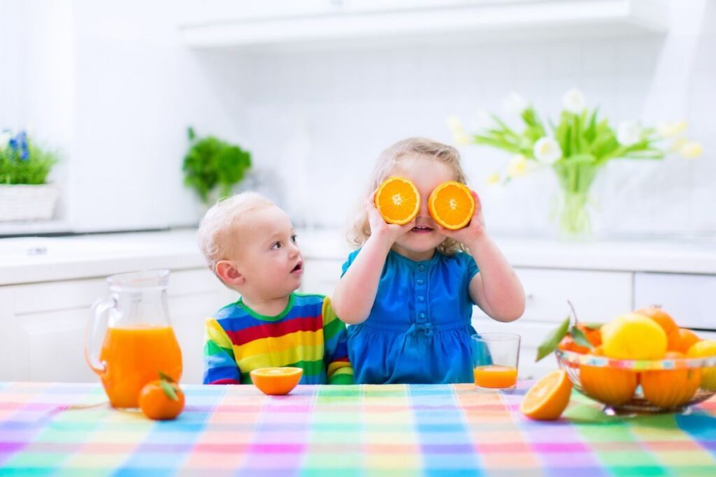 Young children eating oranges at table 